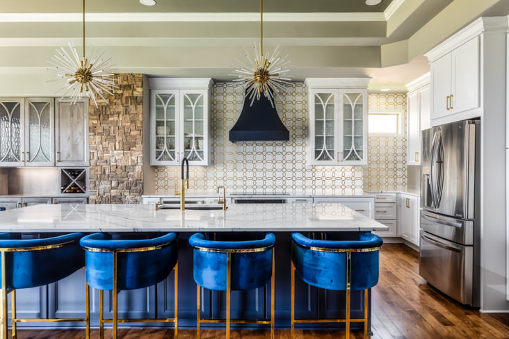 A stunning redesigned kitchen with center island and blue velvet chairs